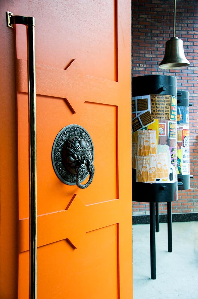 Une immense porte orange ornée d’un symbole de protection invite les hôtes du MOB à la pousser.