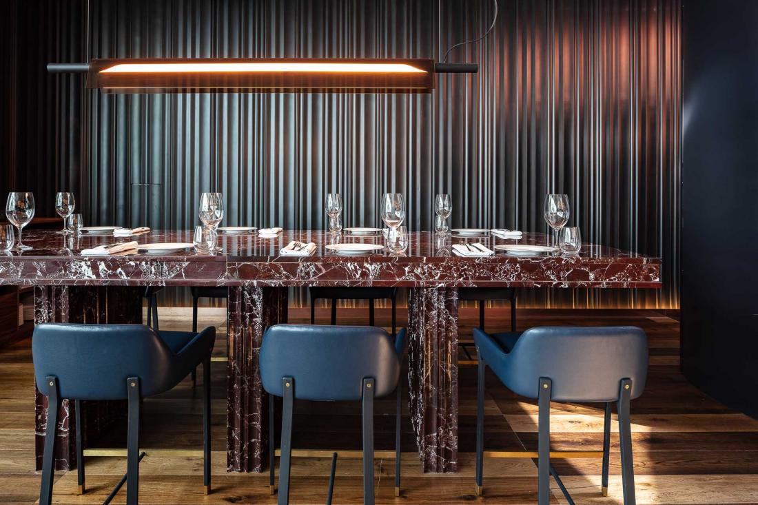 Banquettes en cuir, noyer, détails de cuivre et marbre fauve pour une ambiance intimiste.