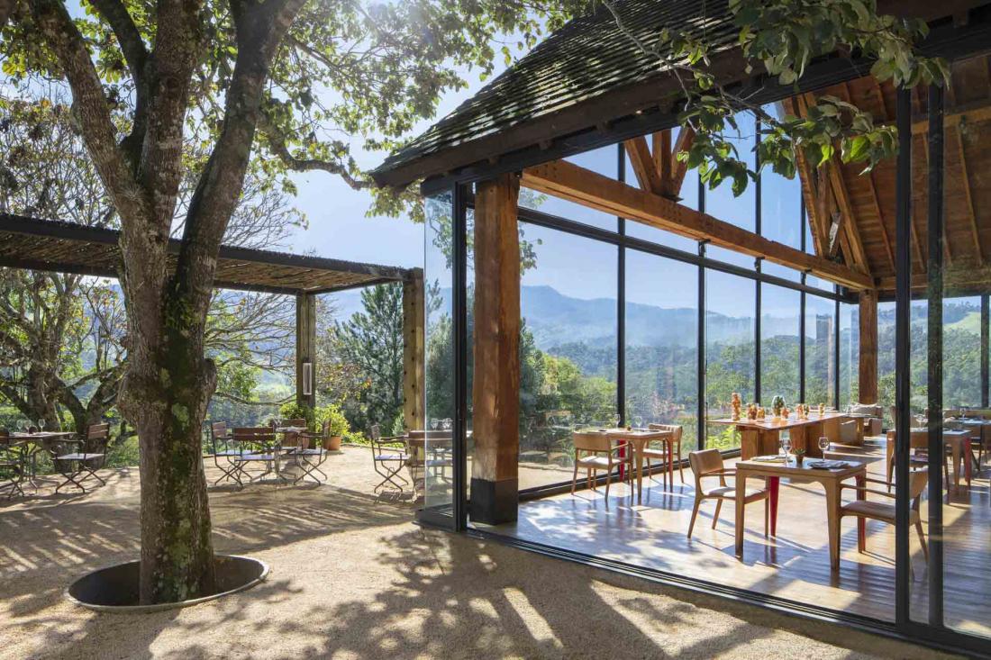 La spacieuse terrasse du restaurant à flanc de colline est ombragée par des auvents naturels