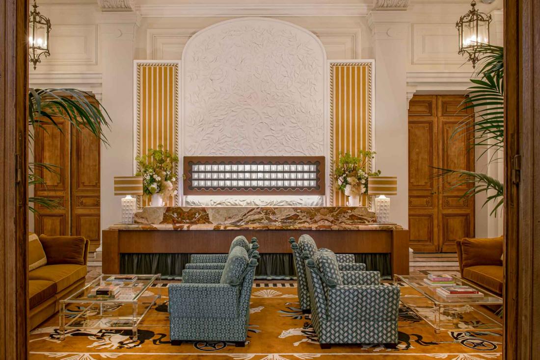 Un lobby de grand hôtel où rien ne manque : panneau à clé, desk en marbre et fauteuils confortables