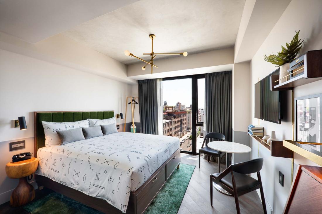 Dans les chambres, les détails en cuivre contrastent avec les plafonds en béton brut et les têtes de lit en mohair vert-gris, bordeaux et bleu marine.