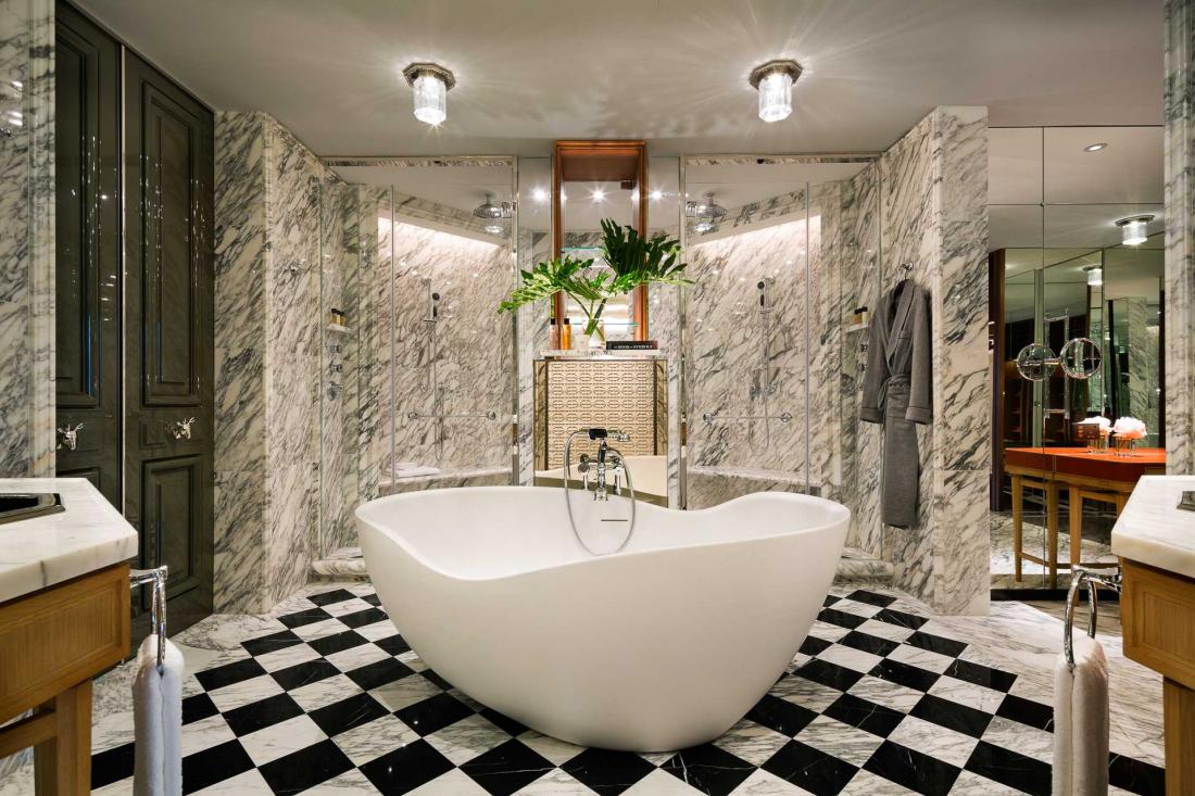 Dans la salle de bain en marbre trône une baignoire de forme libre, avec deux lavabos et deux douches.