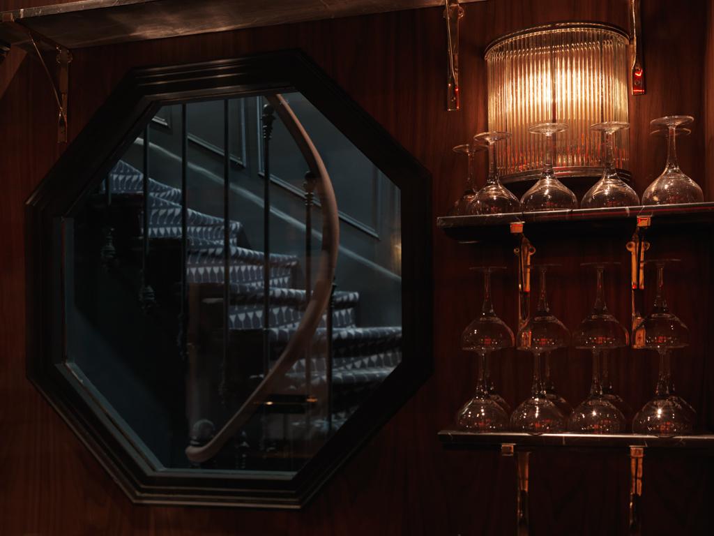 C’est par une ouverture octogonale, un leitmotiv du décor, que l’escalier menant aux chambres se dévoile derrière le bar