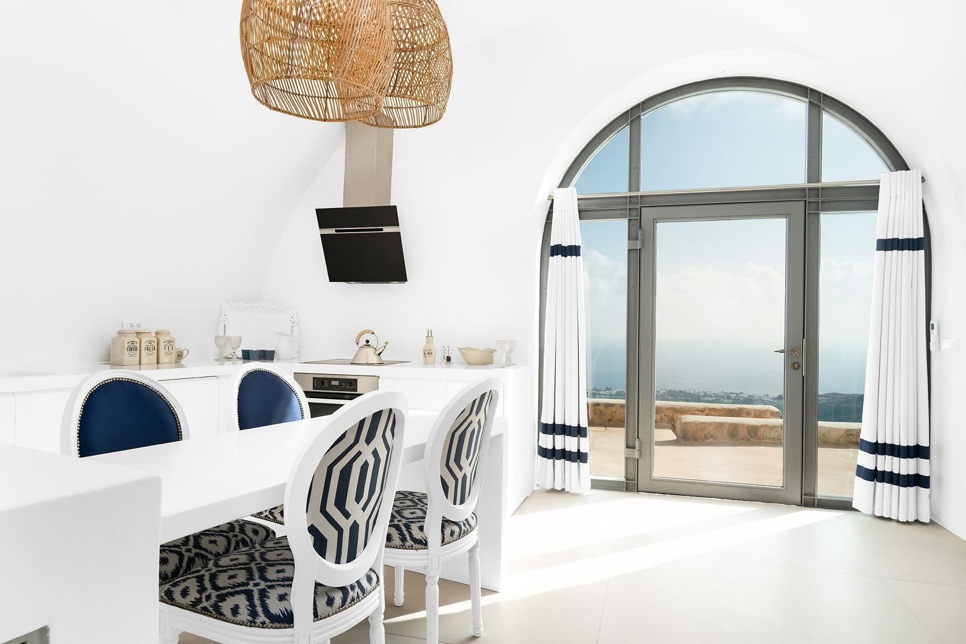 Sous la voûte blanche, la salle à manger s’ouvre par une grande baie cintrée sur la terrasse et l’horizon. L’esprit cycladique revisité dans cette villa de luxe à Santorin. © Blue Villas