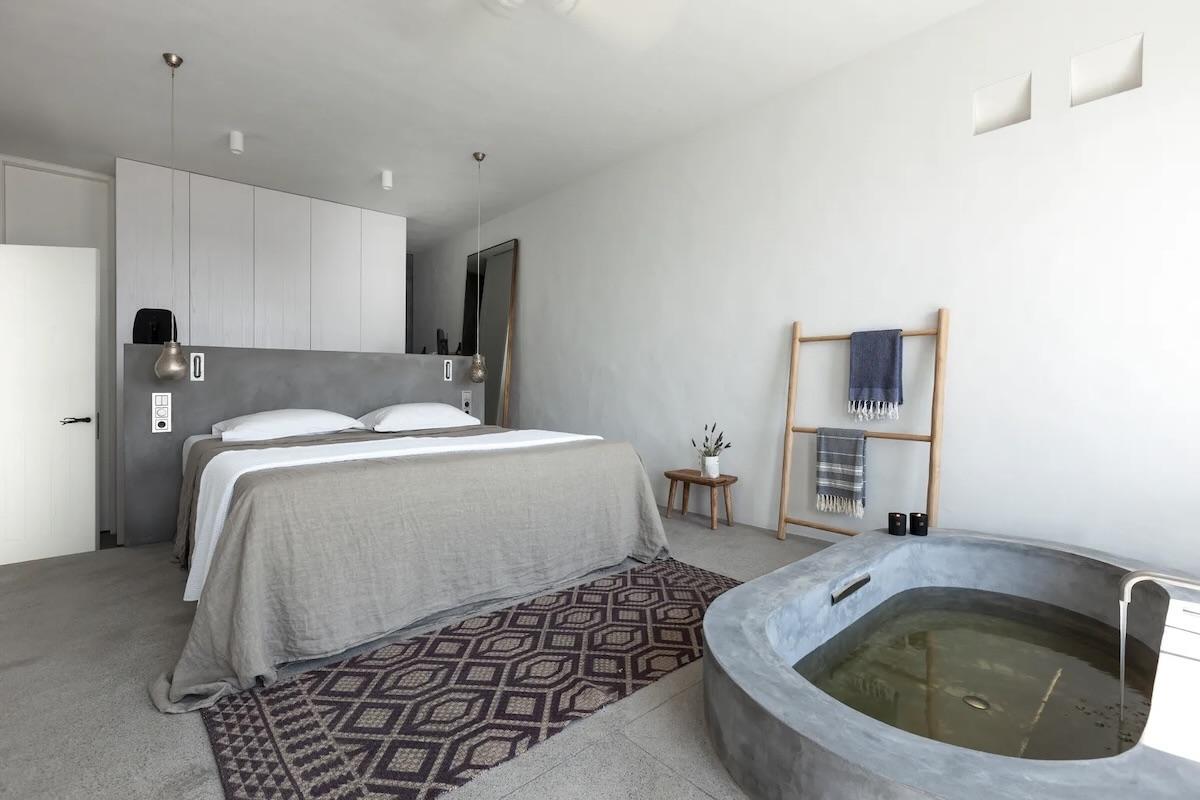 Une baignoire en béton ciré au pied du lit : l’esprit minimaliste de cette villa de luxe dans les Cyclades. © Le Collectionist