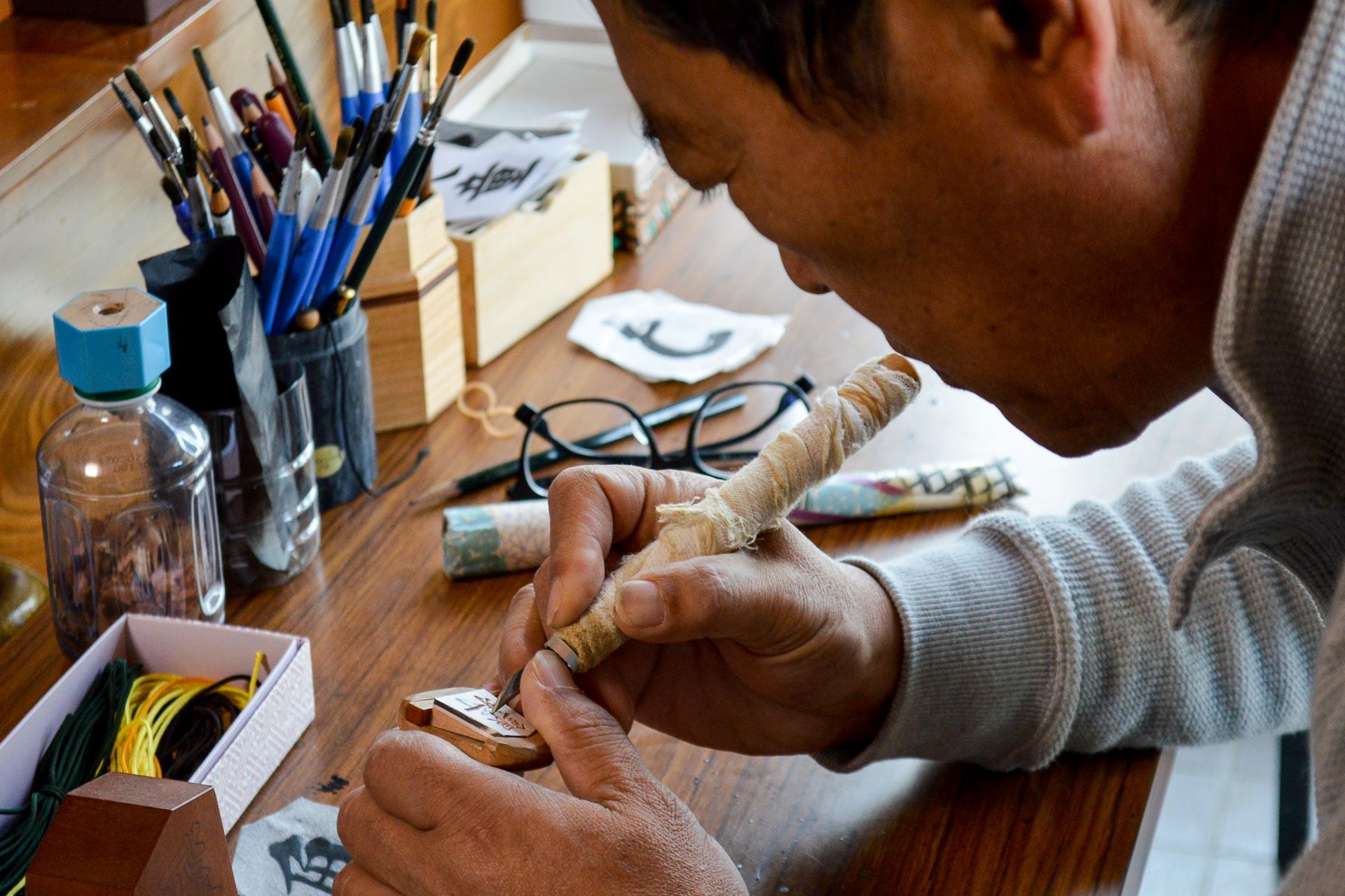 Monsieur Nakajima sculpte la pièce de shogi appelée général d’argent. 