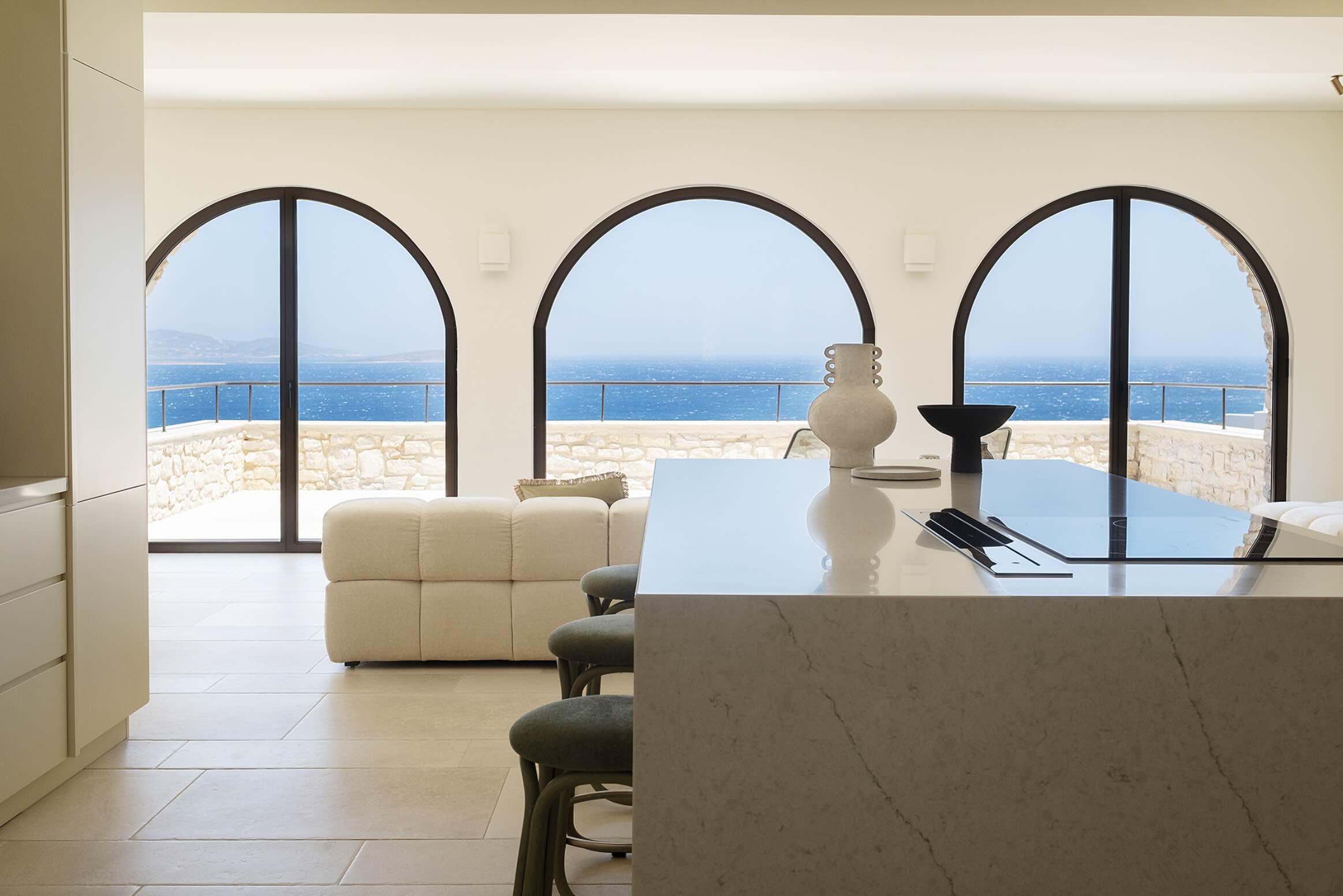 Depuis l’îlot en marbre, trois arches encadrent la mer Égée. Une cuisine ouverte qui donne le ton de cette villa de luxe à Antiparos, dans les Cyclades. © Oliaros Villa Rentals