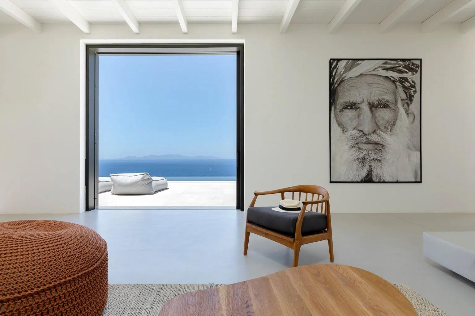 Une large baie cadre la mer comme un tableau : dans le salon de la villa Hébée, villa à louer dans les Cyclades, l’horizon fait partie du décor. © Le Collectionist