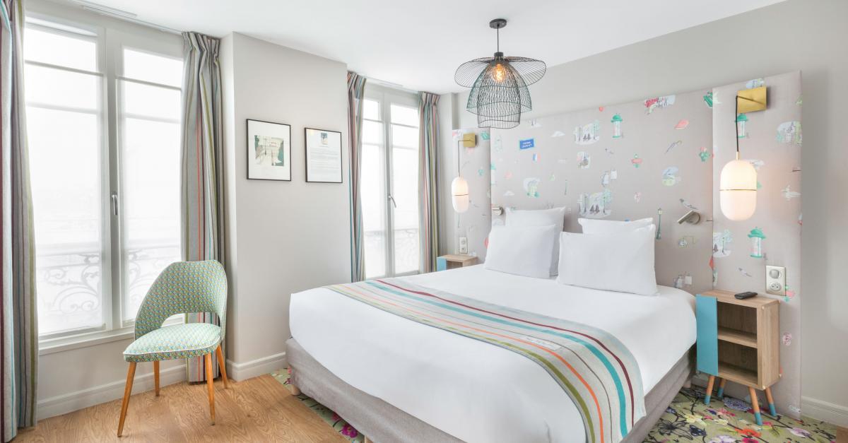 Chambre lumineuse avec décoration subtilement colorée et citation littéraire encadrée. © Hôtel Littéraire Marcel Aymé