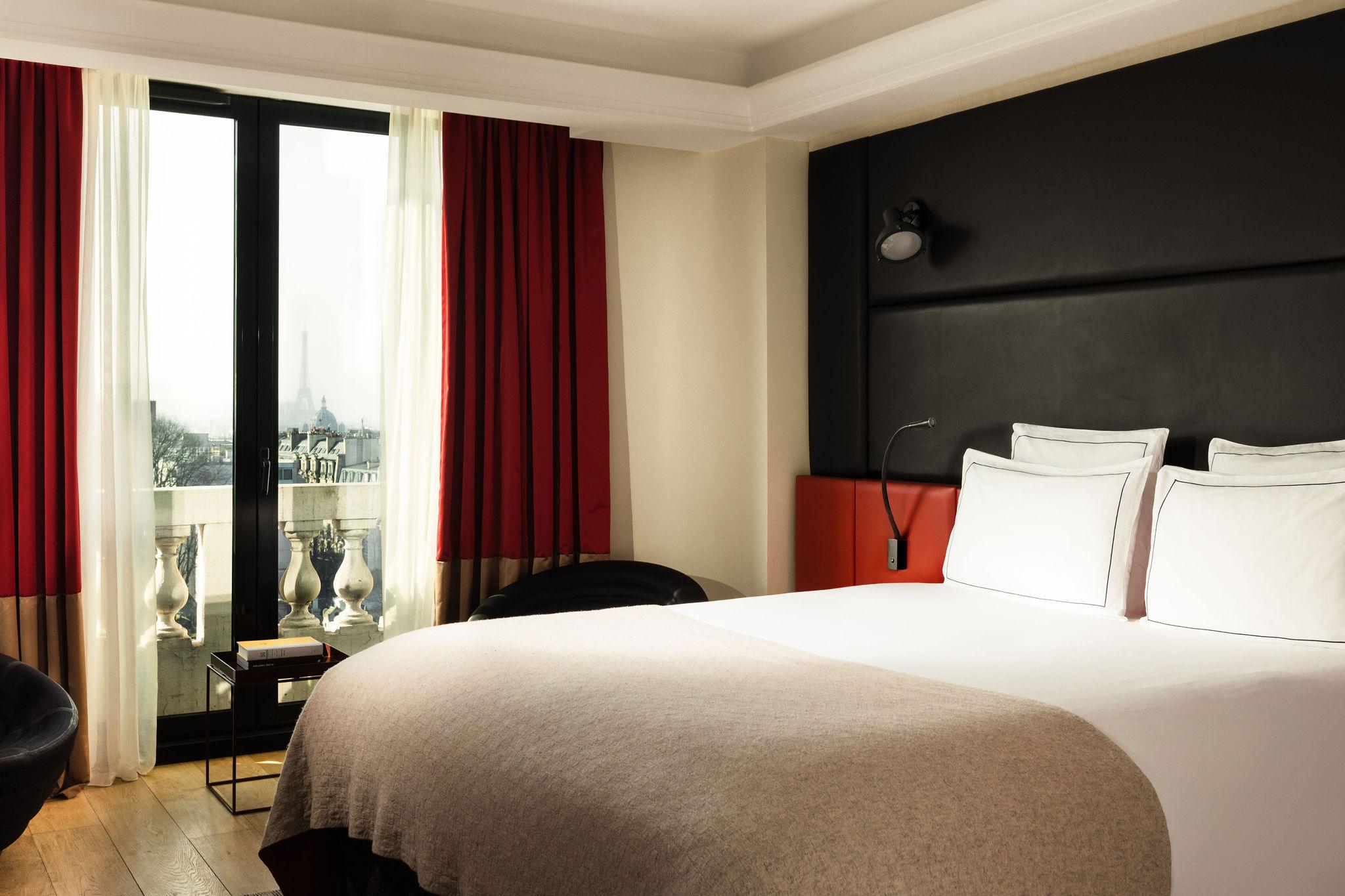 Suite élégante avec lit king-size et balcon offrant une vue sur la Tour Eiffel. © Terrass’ Hotel
