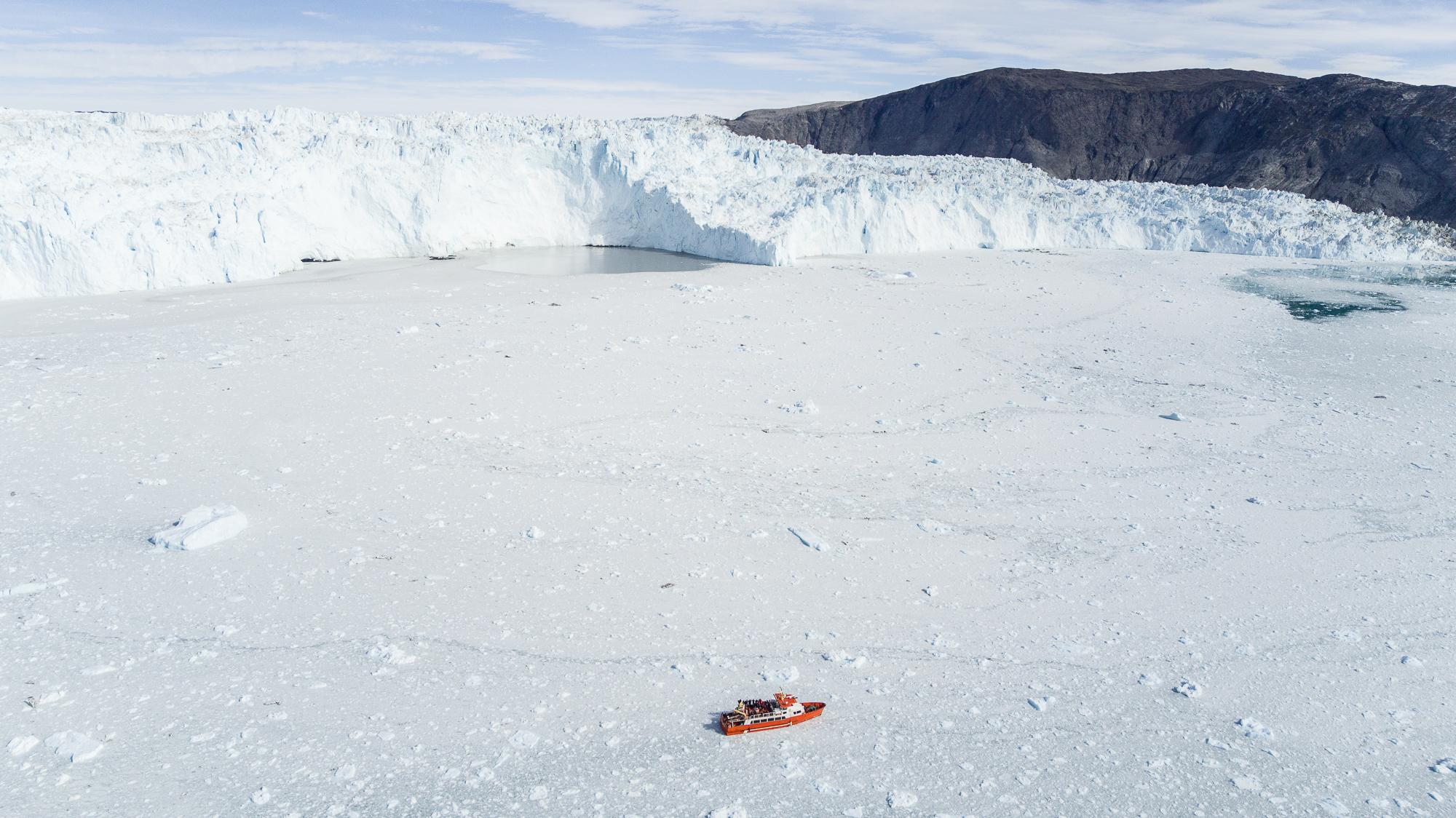 Vue aérienne du glacier d’Eqi. Le vêlage continu du glacier crée un impressionant tapis de glace au milieu duquel navigue le bateau. Celui-ci laissera une partie des voyageurs à l’Eqi Glacier Lodge avant de repartir vers Ilulissat. © DB / Yonder