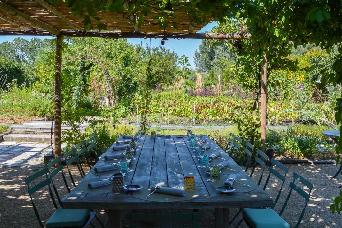 Les grandes tablées en bois face au jardin accueillent les convives en été © Pierre Gunther