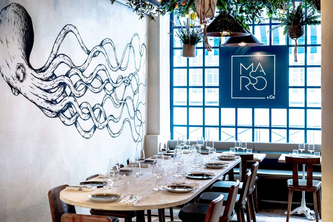 Intérieur du restaurant Marso&co avec sa grande table d'hôtes. Au mur, l'une des fresques de Kraken, street artist parisien renommé © Caspar Miskin