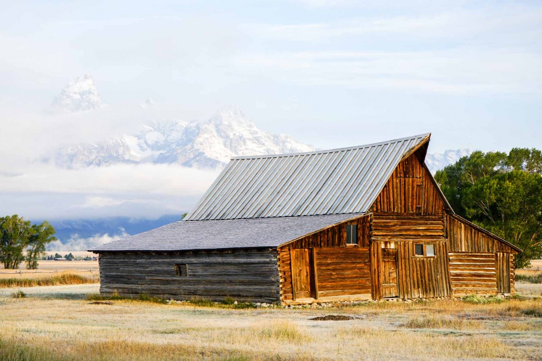 La chaîne de montagnes de Grand Teton, voilé derrière les nuages, prise en photo depuis la Moulton Barn © YONDER.fr