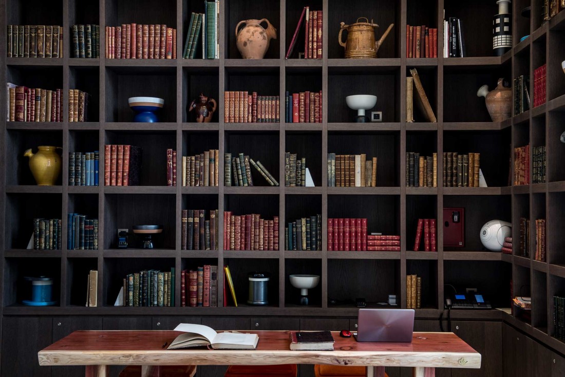 Derrière le bureau de la réception, une immense bibliothèque © Anne-Emmanuelle THION