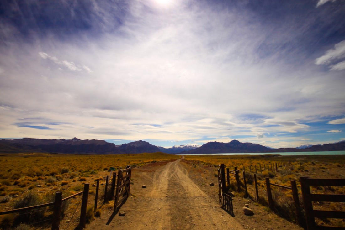 L’entrée de l’Estancia El Cóndor. Plus de 40.000 hectares de terres, de montagnes, de lacs, où pâturent chevaux, guanacos, vaches…  Au loin, les sommets enneigés de la Cordillère des Andes et la frontière chilienne. | © Cédric Aubert