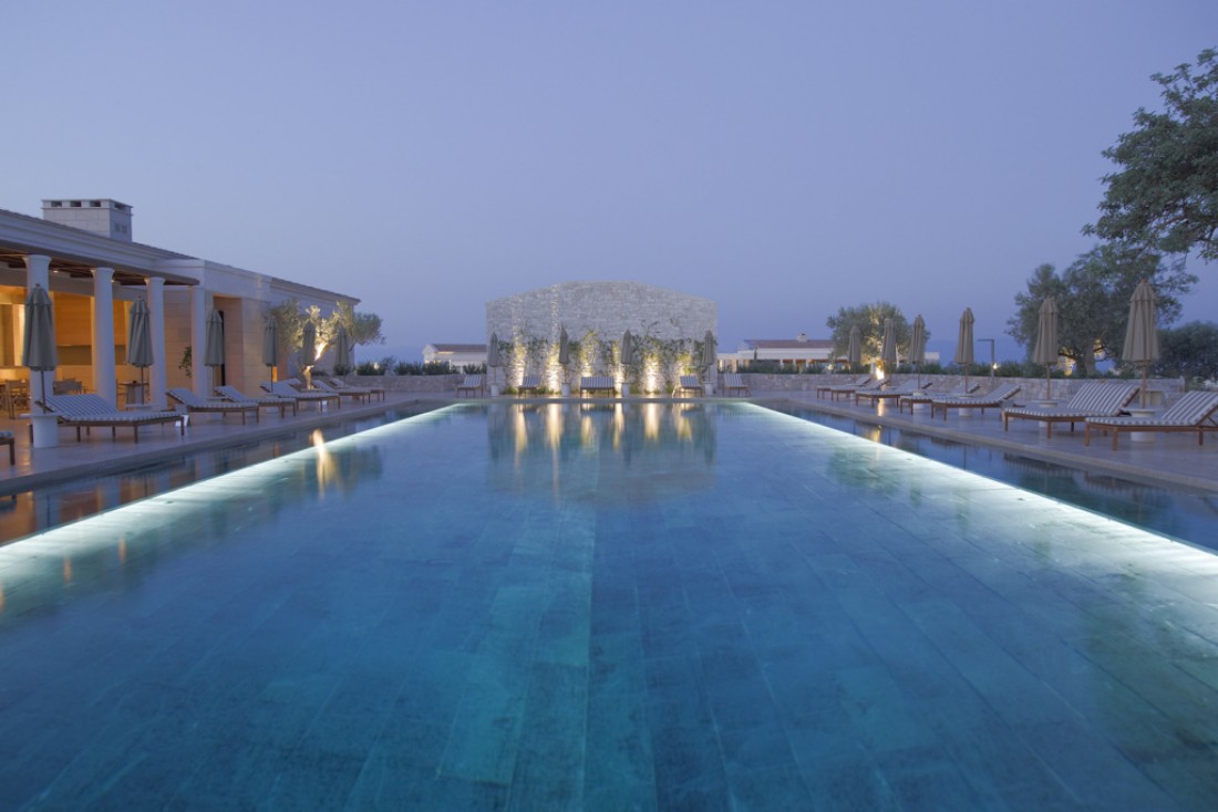 La piscine principale de l'Amanzoe à la tombée de la nuit © Aman