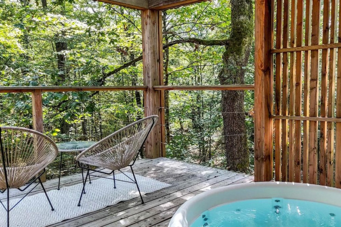 Jacuzzi privé et fauteuils face aux arbres : la terrasse d’un lodge perché à quatre mètres du sol © Loire Valley Lodges