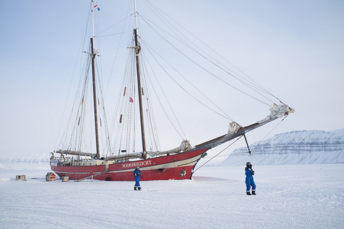 Le <i> Noorderlicht </i> hiverne sur le fjord gelé de Tempelfjorden. Il est possible de déjeuner ou de passer la nuit à bord en réservant un tour avec Basecamp Spitsbergen.
