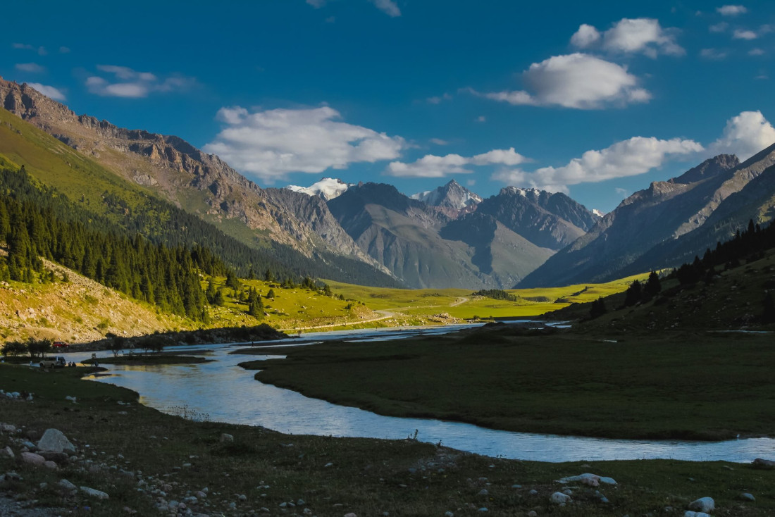 Vallée de montagne près de Karakol, au Kirghizistan, avec une rivière serpentant entre pâturages et sommets enneigés en arrière-plan © Unsplash / Above Horizon