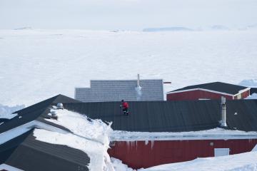 Un enfant jouant sur le toit, rendu facilement accessible par les tas de neige accumuléeau pied des batiments.